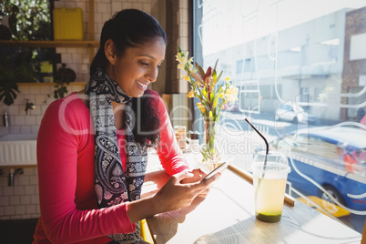 Woman using phone at window sill in cafe