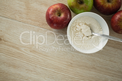 Directly above shot of flour in bowl by apples
