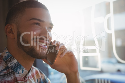 Young man talking on phone in cafe