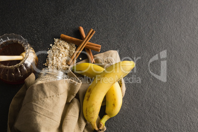Honey, banana, oatmeal, cinnamon sticks on black background