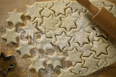 Star shape cookies on dough with rolling pin