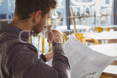 Businessman reading newspaper while having coffee