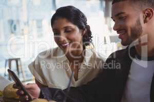 Man with woman using phone in cafe