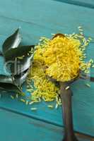 Raw organic yellow rice and curry leaves on wooden table