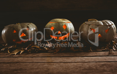 Jack o lanterns with autumn leaves arranged on table