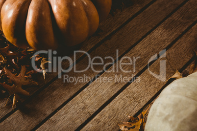 Autumn leaves by pumpkins on wooden table