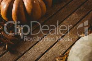 Autumn leaves by pumpkins on wooden table