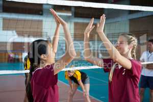 Female players giving high five to each other in volleyball court