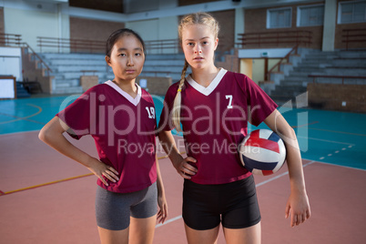 Female players standing together with ball in the volleyball court