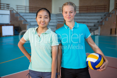 Smiling volleyball players standing together with ball in the court