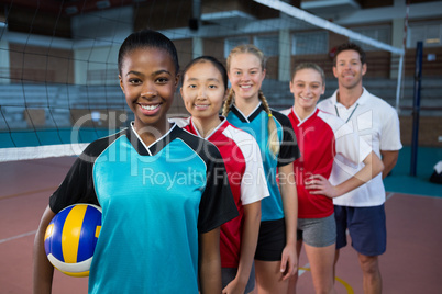 Male coach and volleyball players standing in a row