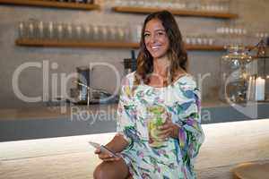 Portrait of beautiful woman using mobile phone while having mocktail