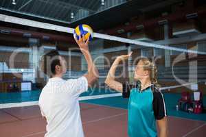 Male coach assisting volleyball player