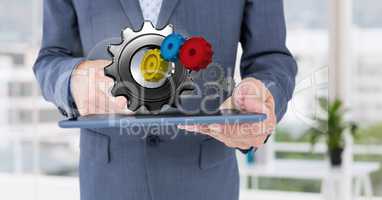 business man holding tablet with 3 d cogs on it