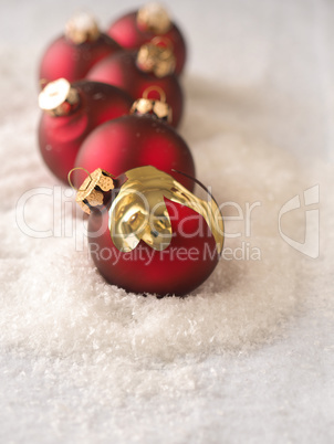 Old red Christmas baubles in snow