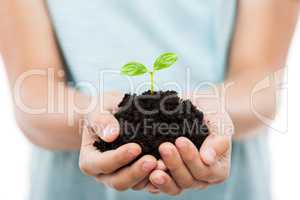 Human hand holding green sprout leaf growth at dirt soil