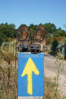 Kaputte Wanderschuhe auf einer Wegmarkierung des Jakobsweges, Spanien