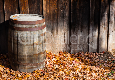 Old wooden cask against wall boards in autumn.