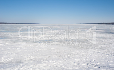 Frozen bay covered in ice under clear blue sky.