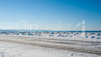 Frozen ice and sand dunes on beach in winter.