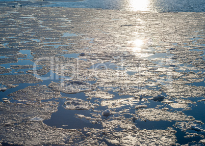 Melting ice sheet on water reflecting sunlight.