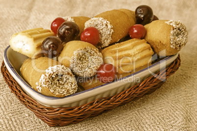 Cookies and cherries on the plate in a wicker basket.