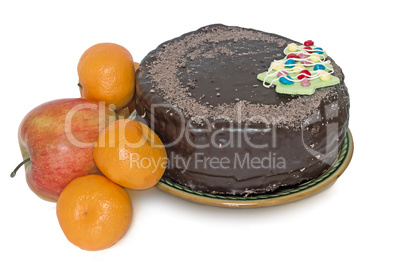 Chocolate cake on a ceramic platter and fruit on a white backgro
