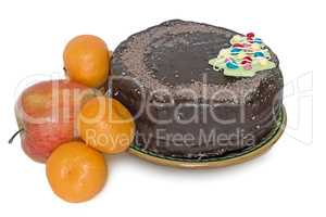 Chocolate cake on a ceramic platter and fruit on a white backgro