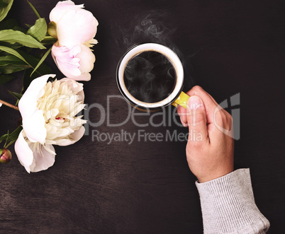 cup of hot black coffee in a human hand