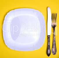 empty white square plate and metal fork and knife