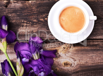 cup of black coffee with a bouquet of blue irises
