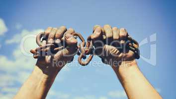two dirty male hands wrapped in a rusty iron chain