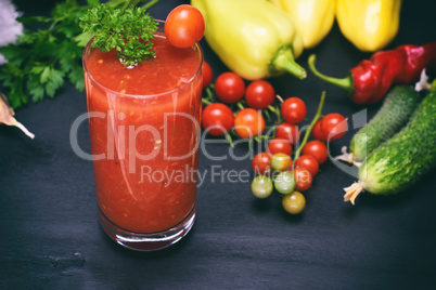 a glass of tomato juice on a black table