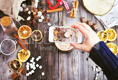 a white smartphone in a woman's hand takes a photograph of a mug