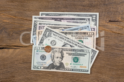 Dollar banknotes and a coin on wooden background.