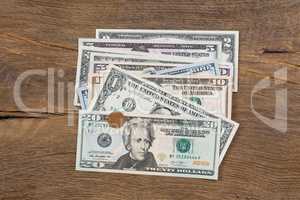 Dollar banknotes and a coin on wooden background.
