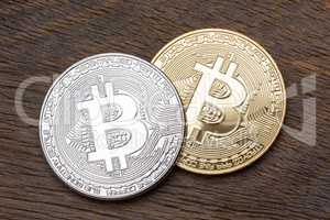 Silver and golden bitcoins on wooden background, close up.