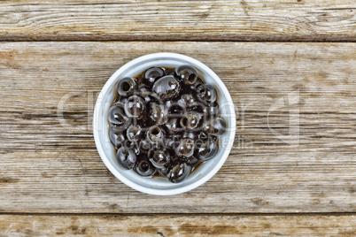 Olives in a white bowl on a wooden table