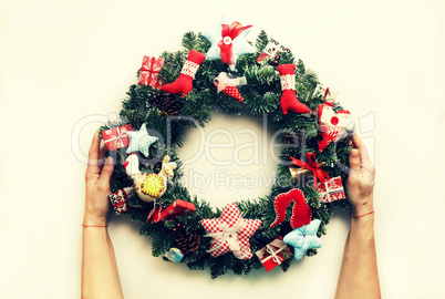 A decorated Christmas wreath in the hands of a woman. Isolated on white background