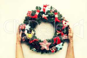 A decorated Christmas wreath in the hands of a woman. Isolated on white background