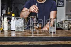 The barman is preparing a cocktail at the bar
