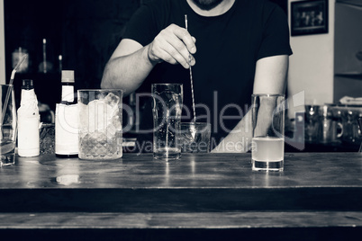 The barman is preparing a cocktail at the bar