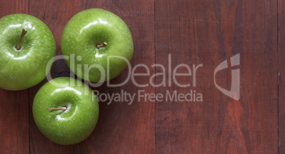 Green ripe apples on a wooden background.