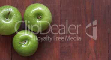 Green ripe apples on a wooden background.