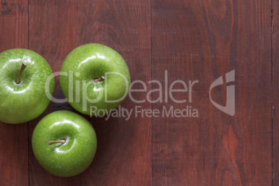 Green ripe apples on a wooden background.