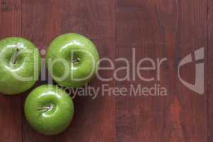 Green ripe apples on a wooden background.