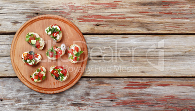 Delicious Italian bruschetta with roasted tomatoes, mozzarella cheese and herbs on a cutting board