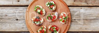 Delicious Italian bruschetta with roasted tomatoes, mozzarella cheese and herbs on a cutting board