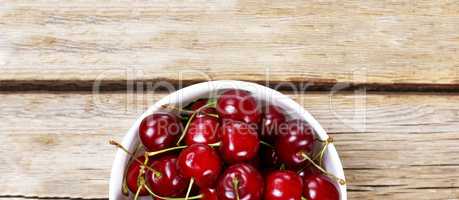 Ripe Cherry  In a white bowl on a wooden background, rural style. View from above