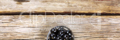 Black olives on a wooden background. View from above